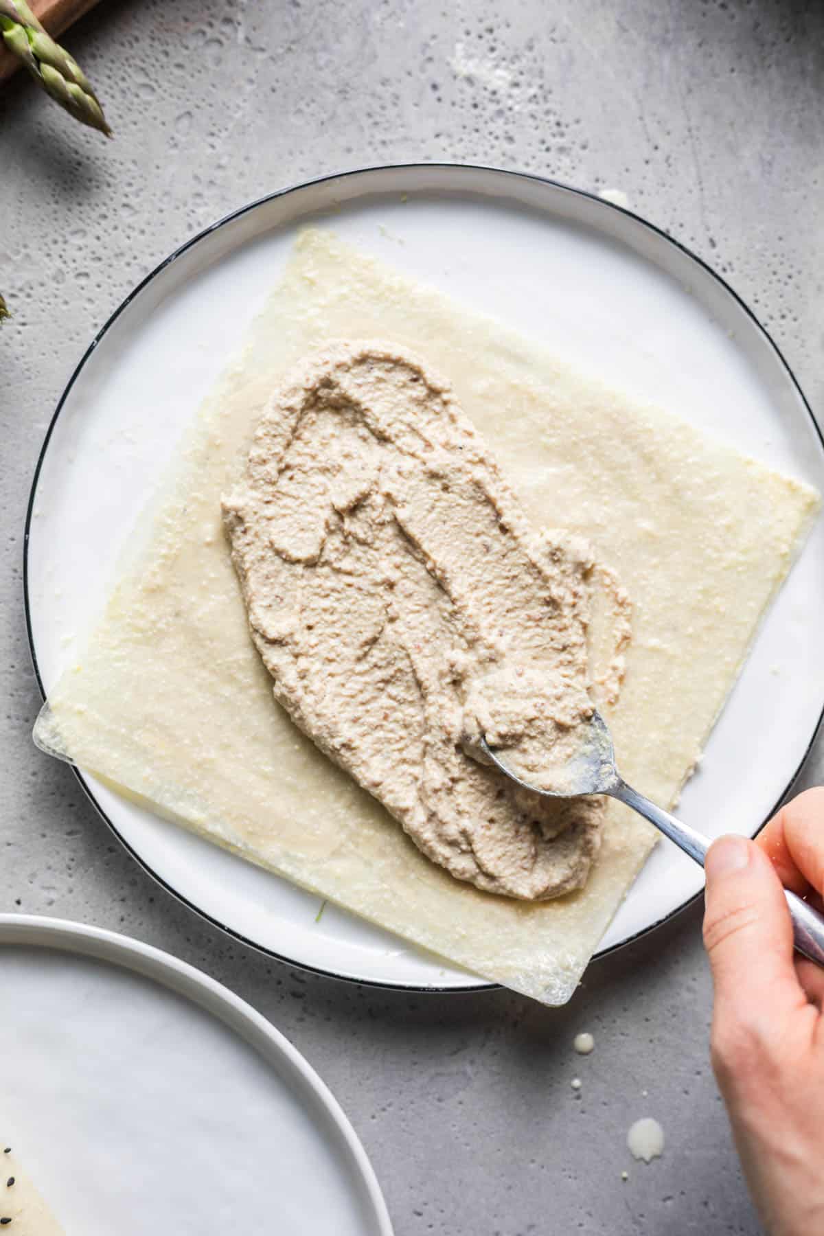 Spreading smoked tofu cream onto a soaked rice paper sheet
