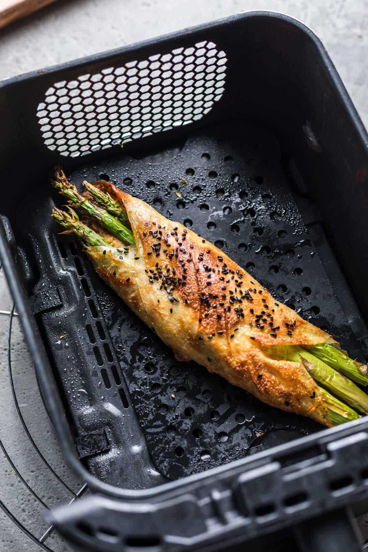 Vegan asparagus parcel cooking in the air fryer basket