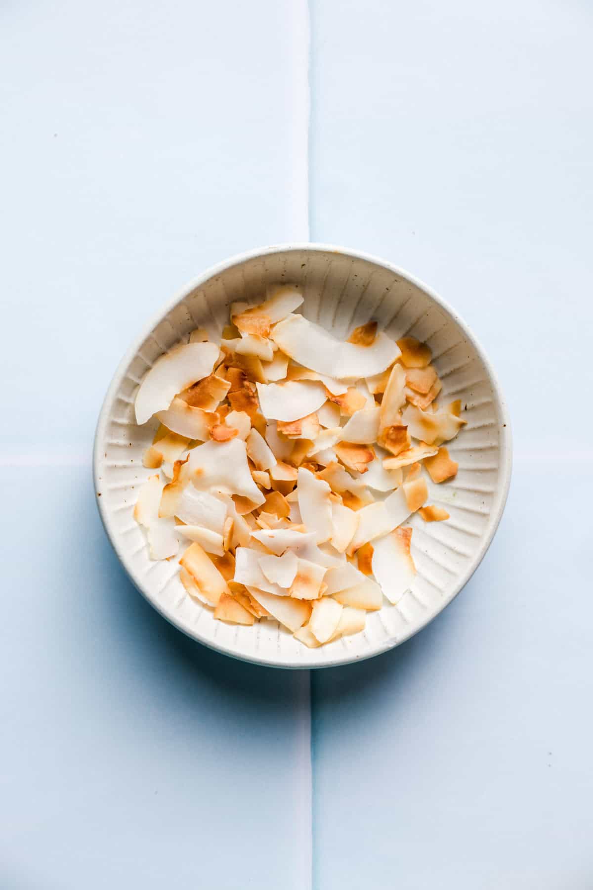 Coconut flakes being toasted in a pan until golden