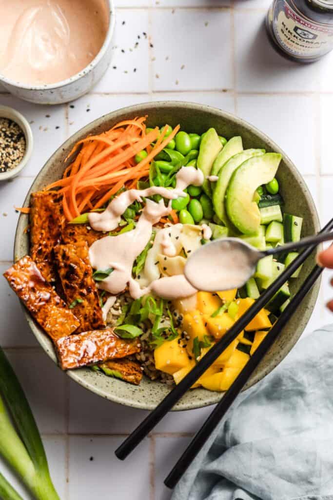 Vegan sushi bowl with pan-fried tempeh, avocado, mango, edamame and carrot