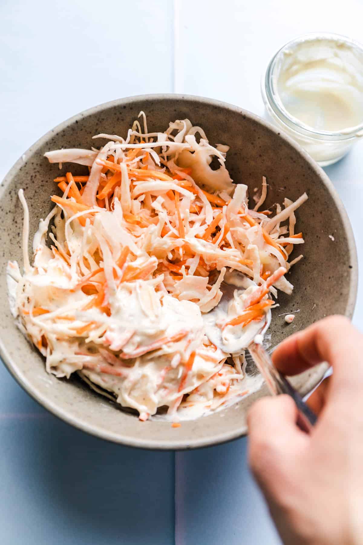 Mixing creamy vegan coleslaw in a bowl