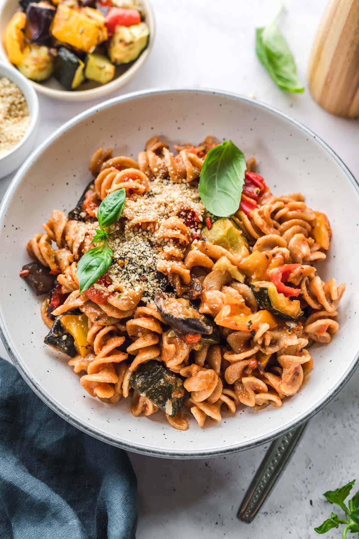 vegan ratatouille pasta with roasted vegetables, garnished with fresh basil