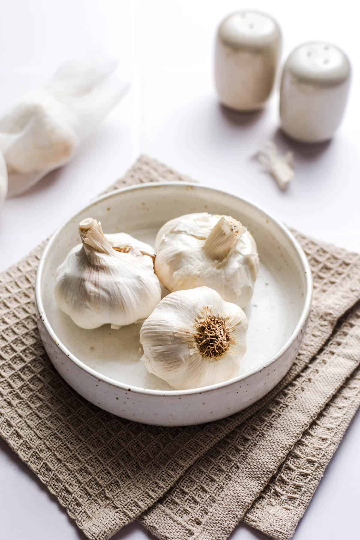 Whole garlic bulbs and loose cloves in a bowl before roasting