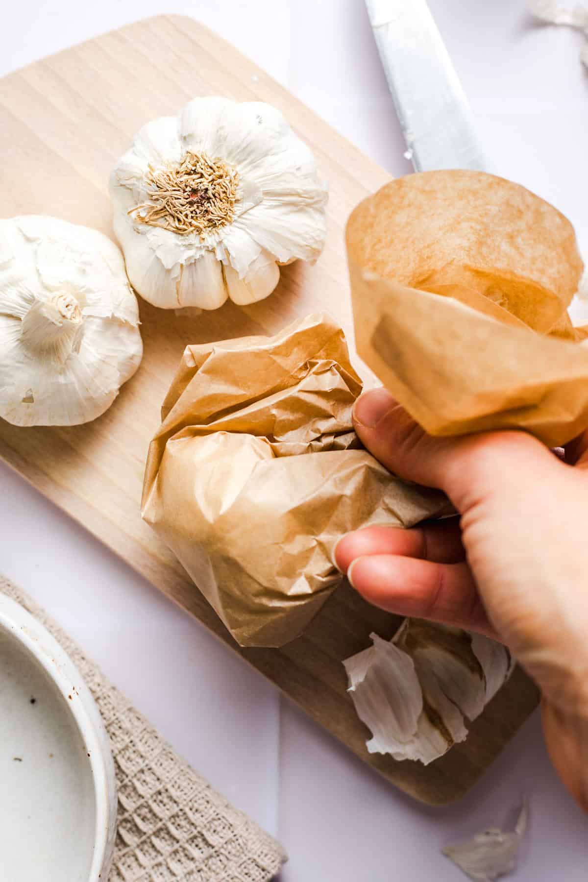 Garlic bulbs wrapped in parchment paper before air frying