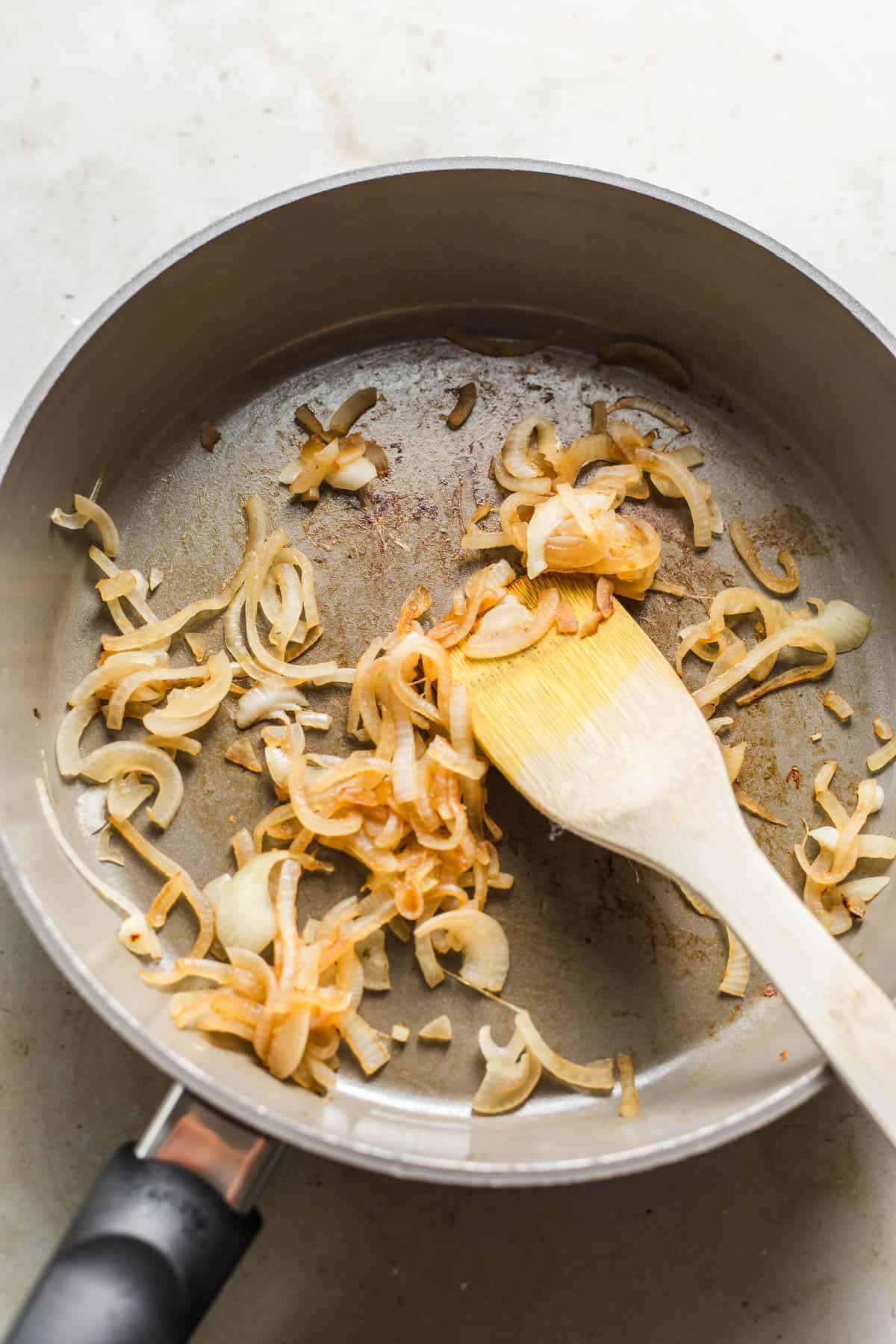 Sauteing sliced onions in a skillet for vegan stroganoff