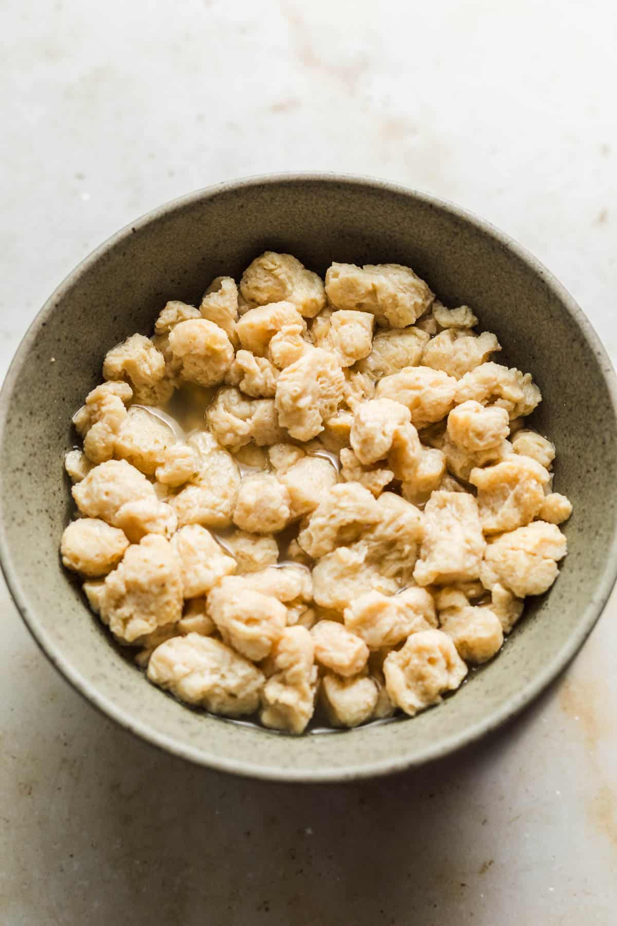 Soaking soy curls in hot vegetable broth in a bowl