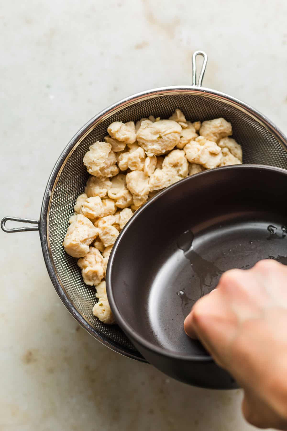 Squeezing soaked soy curls to remove excess liquid before searing