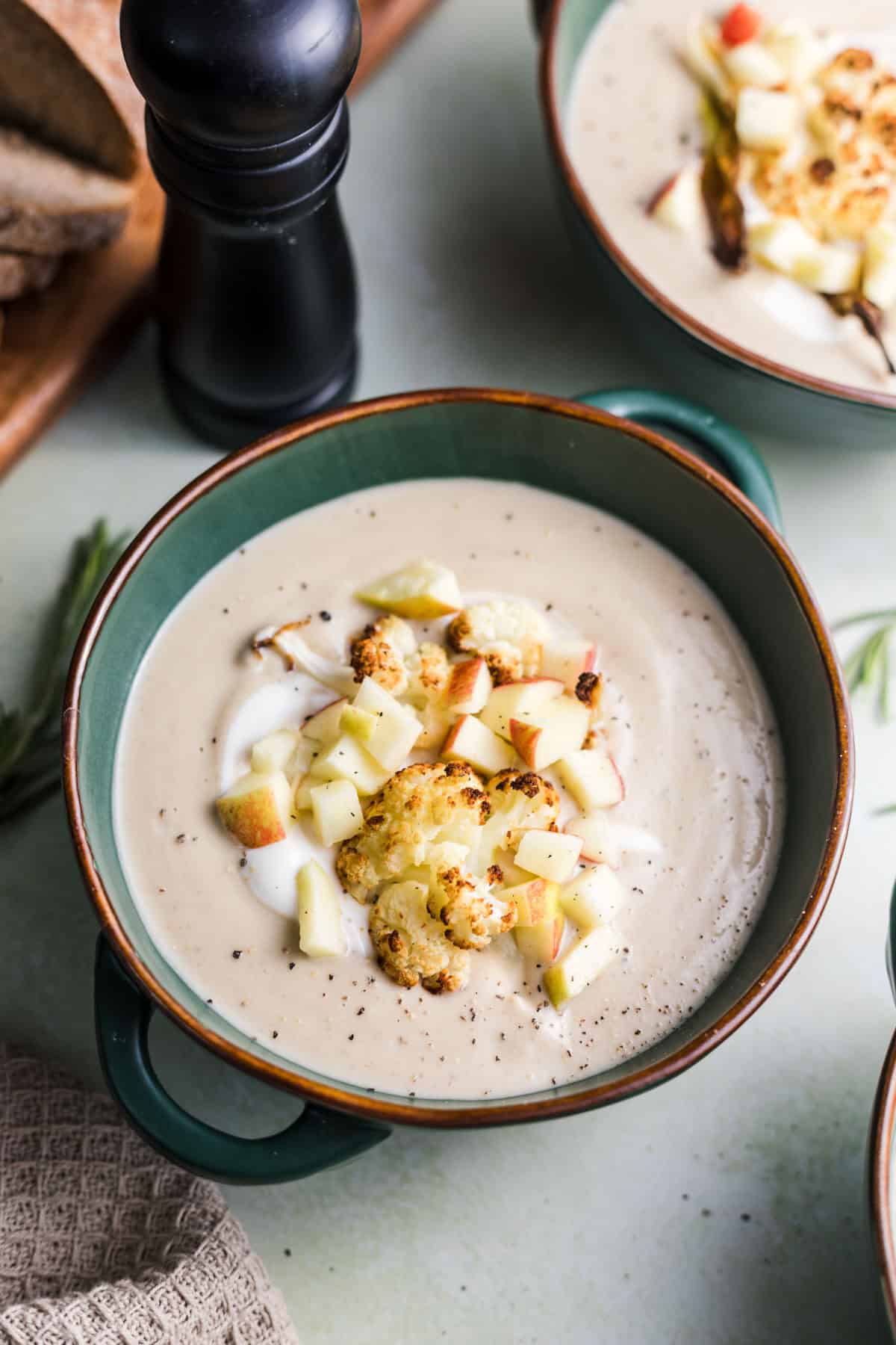 Creamy vegan cauliflower soup with chestnuts garnished with roasted florets and diced apple