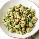 Bowl of vegan pesto pasta with peas, arugula and pine nuts