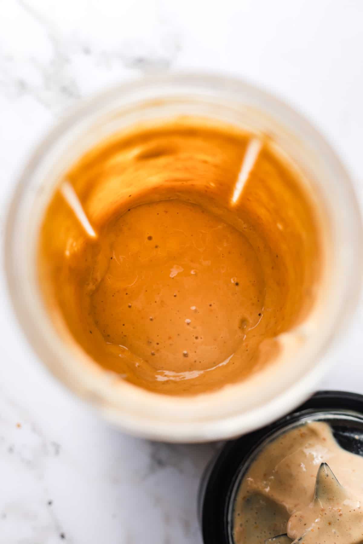 Blending silken tofu with sun-dried tomatoes and nutritional yeast until creamy