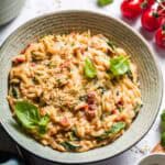 Creamy vegan tomato orzo in a bowl with fresh basil