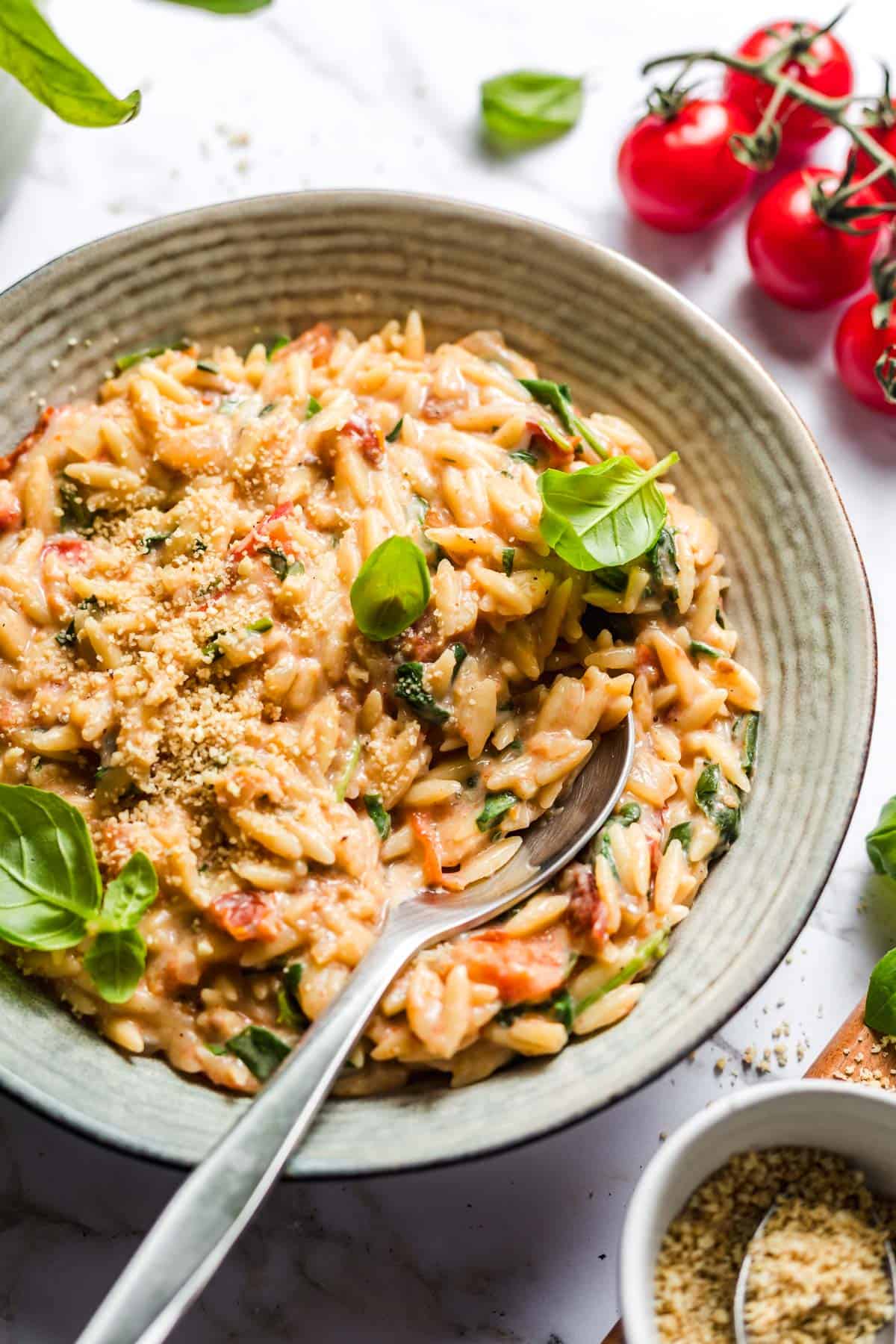 Creamy vegan tomato orzo garnished with fresh basil, served from above