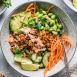 Vegan tempeh vegetable bowl with rice, edamame, avocado and bang bang sauce
