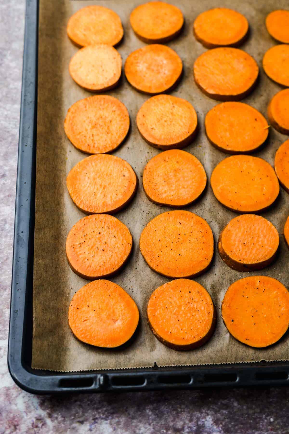 Sliced sweet potato rounds arranged on a baking sheet before roasting