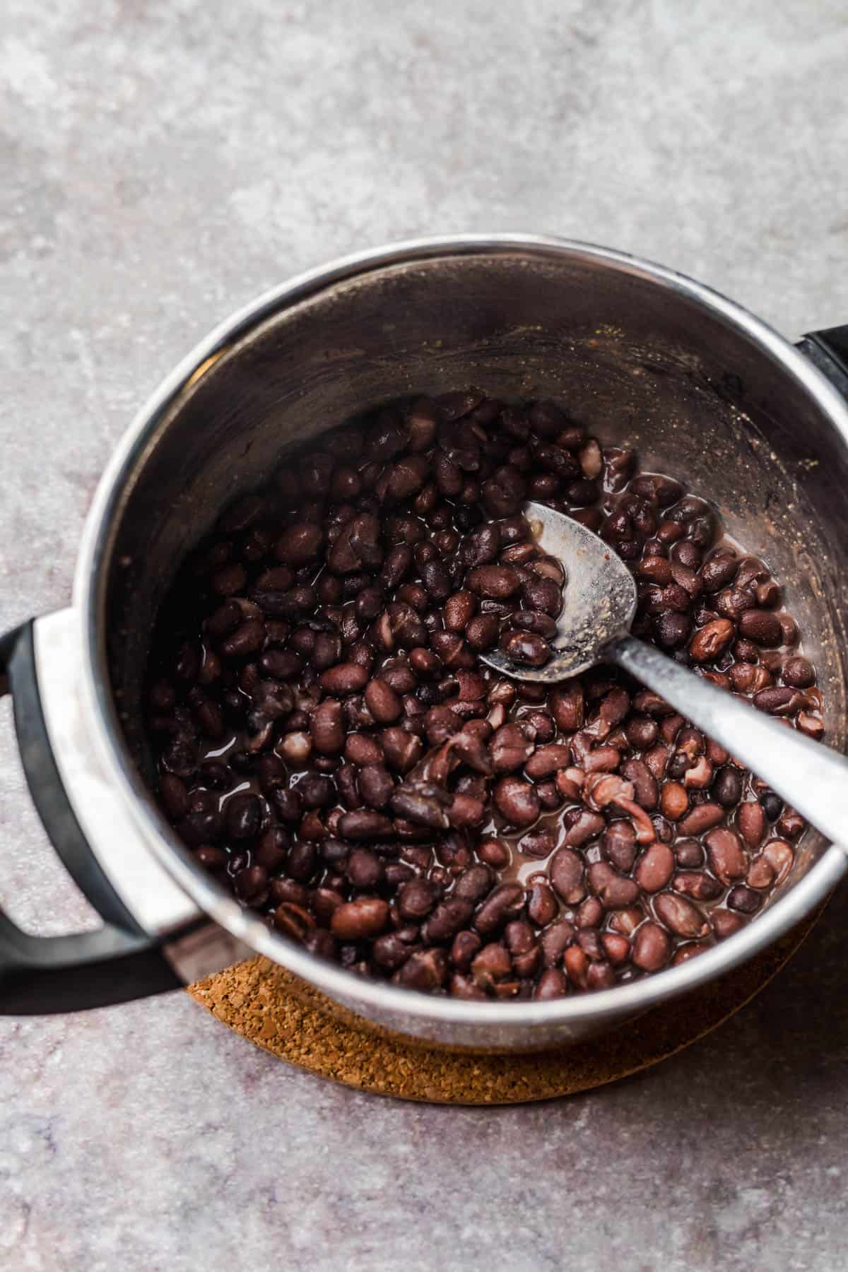 Black beans simmering in a pot with cumin and lime juice