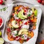 Loaded vegan sweet potato nachos drizzled with vegan nacho cheese sauce, black beans, and avocado