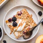 Vegan baked oats topped with coconut yogurt, blackberries and a caramel drizzle on a plate