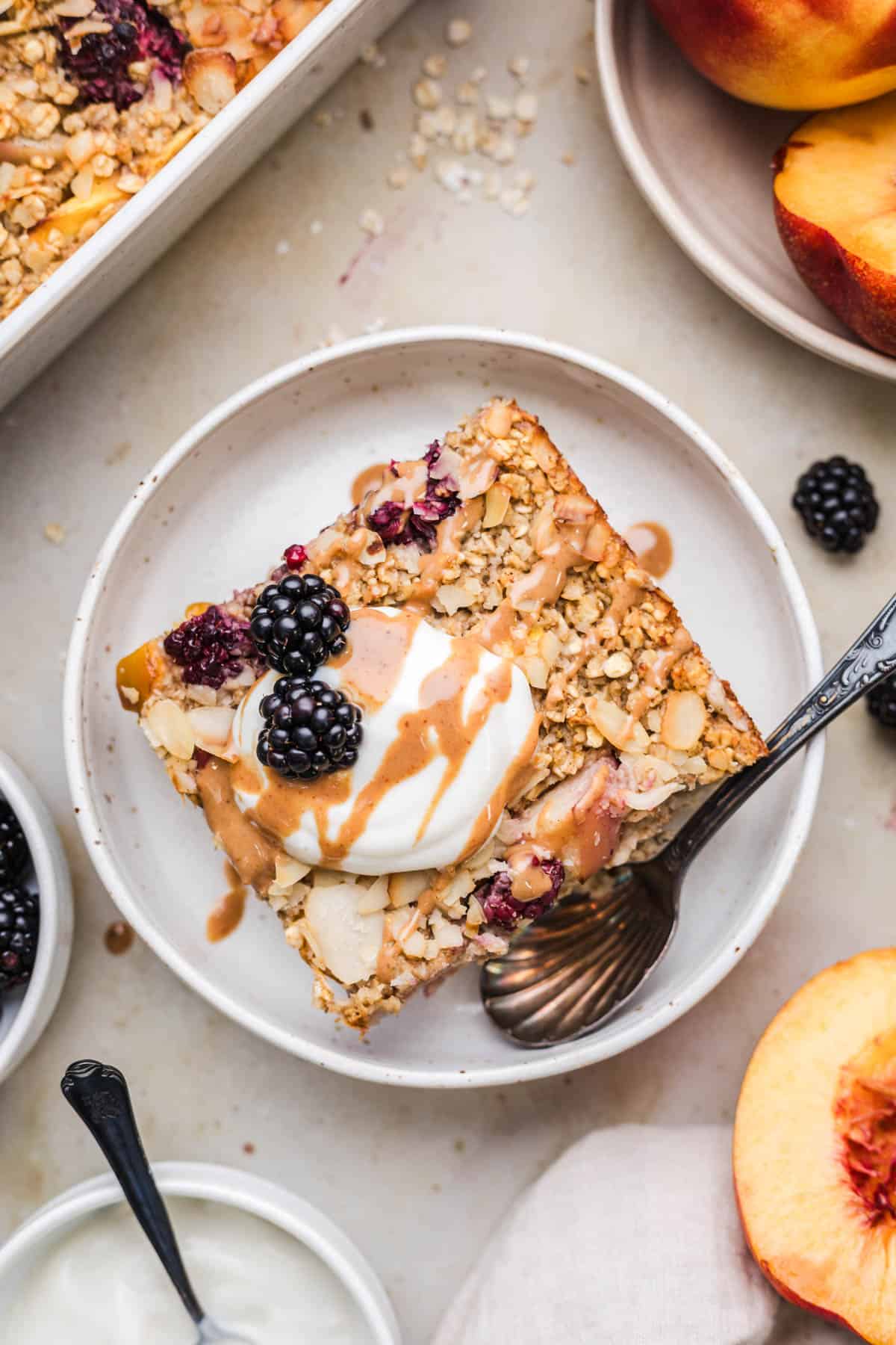 Vegan baked oats topped with coconut yogurt, blackberries and a caramel drizzle on a plate