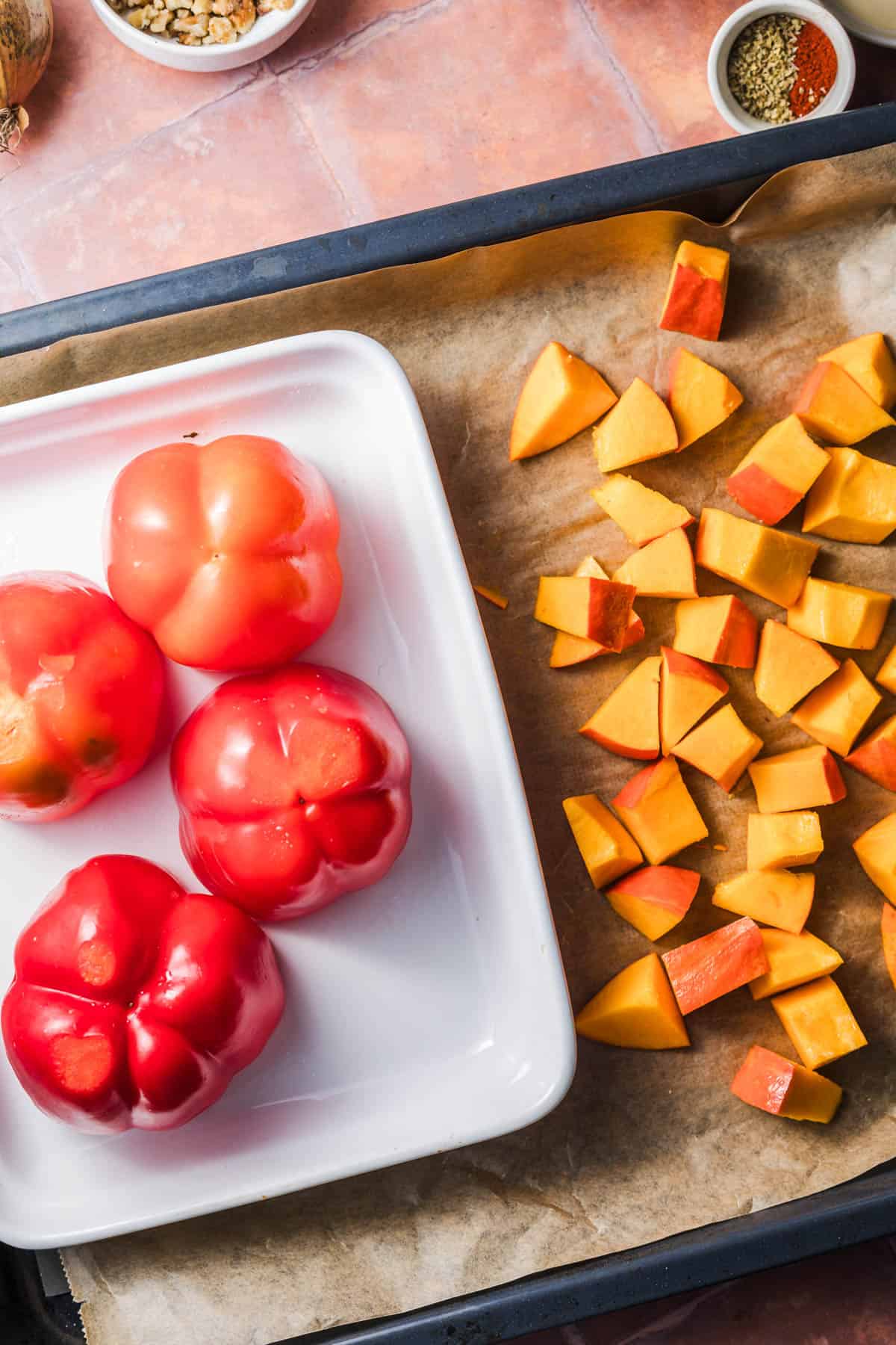 Red bell peppers and diced hokkaido pumpkin on a baking sheet