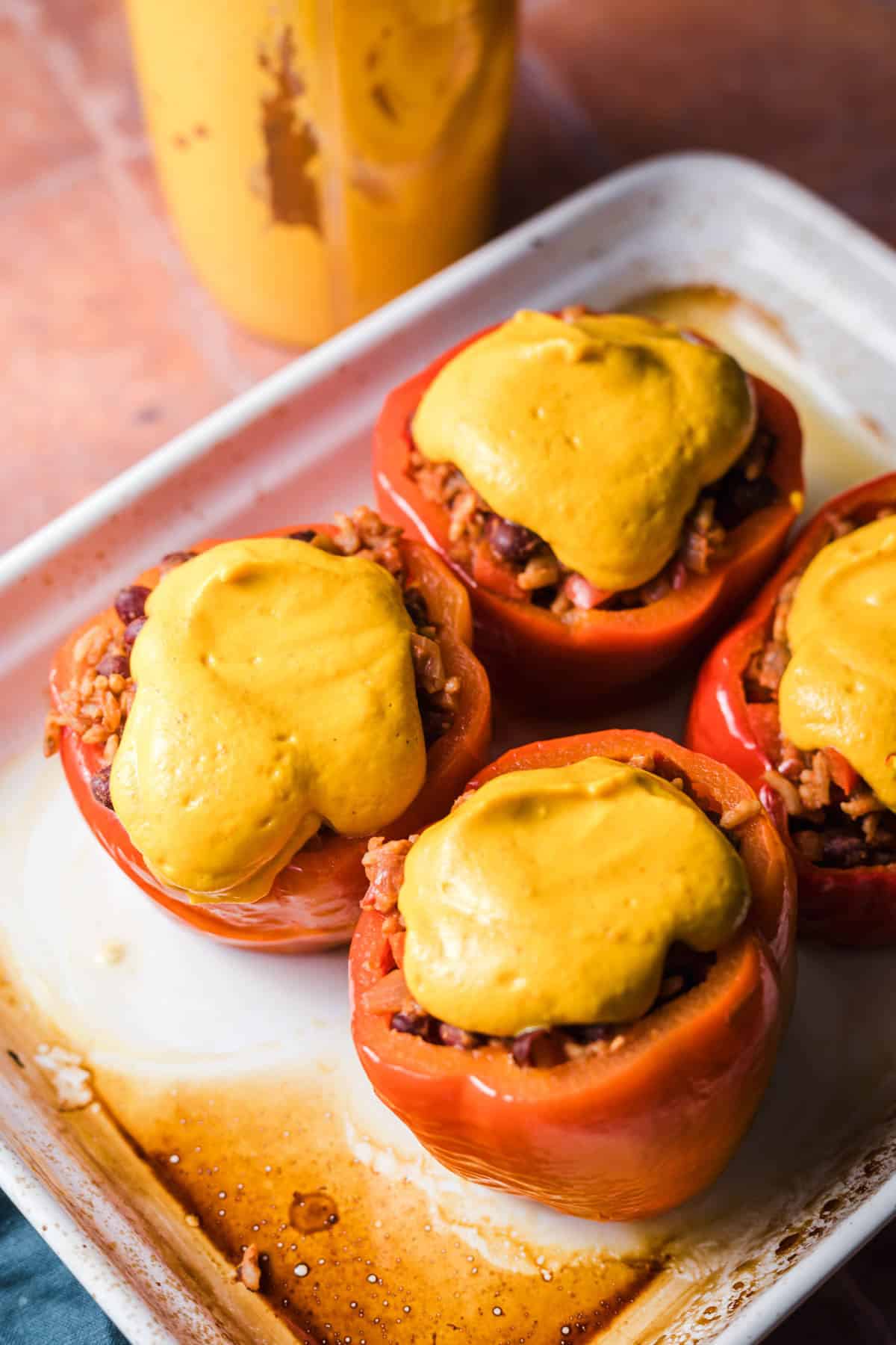 Vegan stuffed peppers topped with pumpkin cream before baking