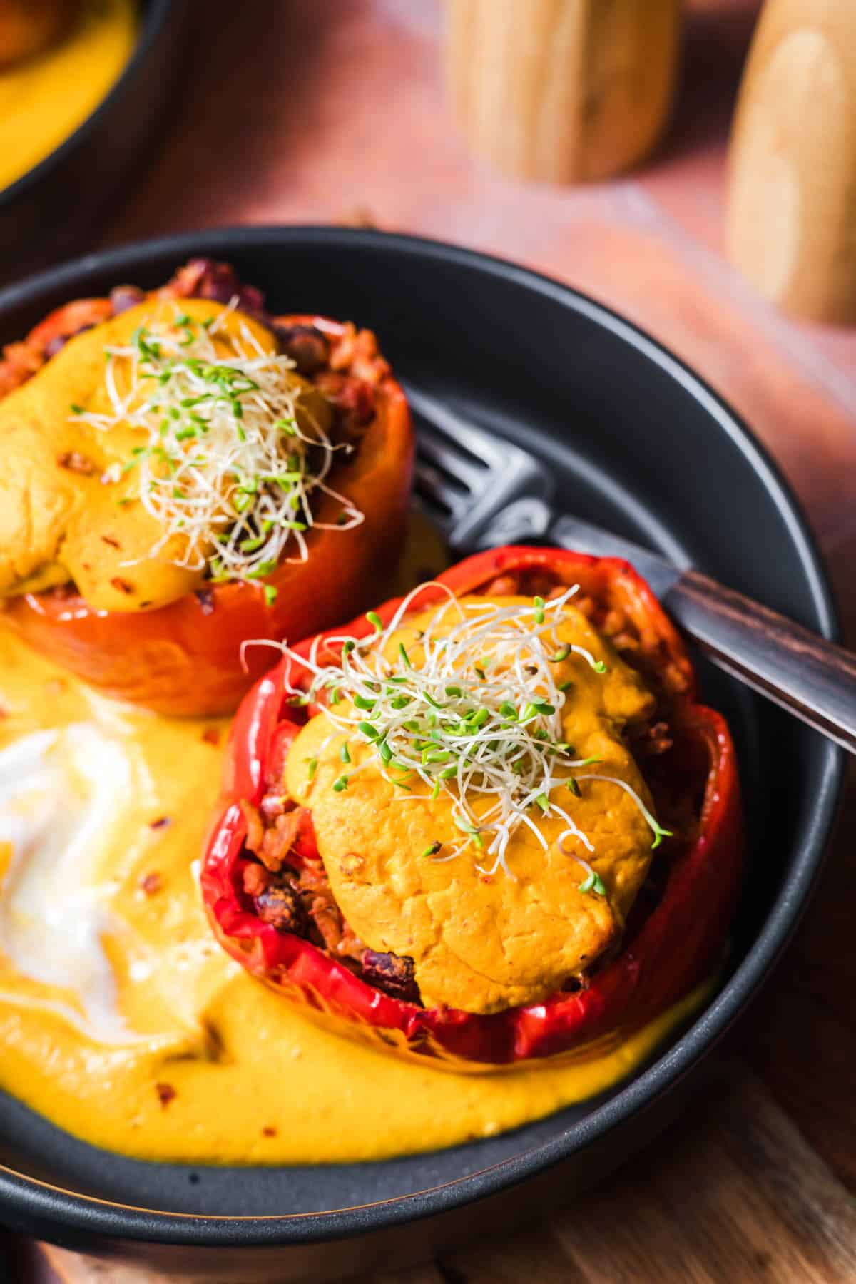 Vegan stuffed peppers with rice and kidney beans served with pumpkin sauce