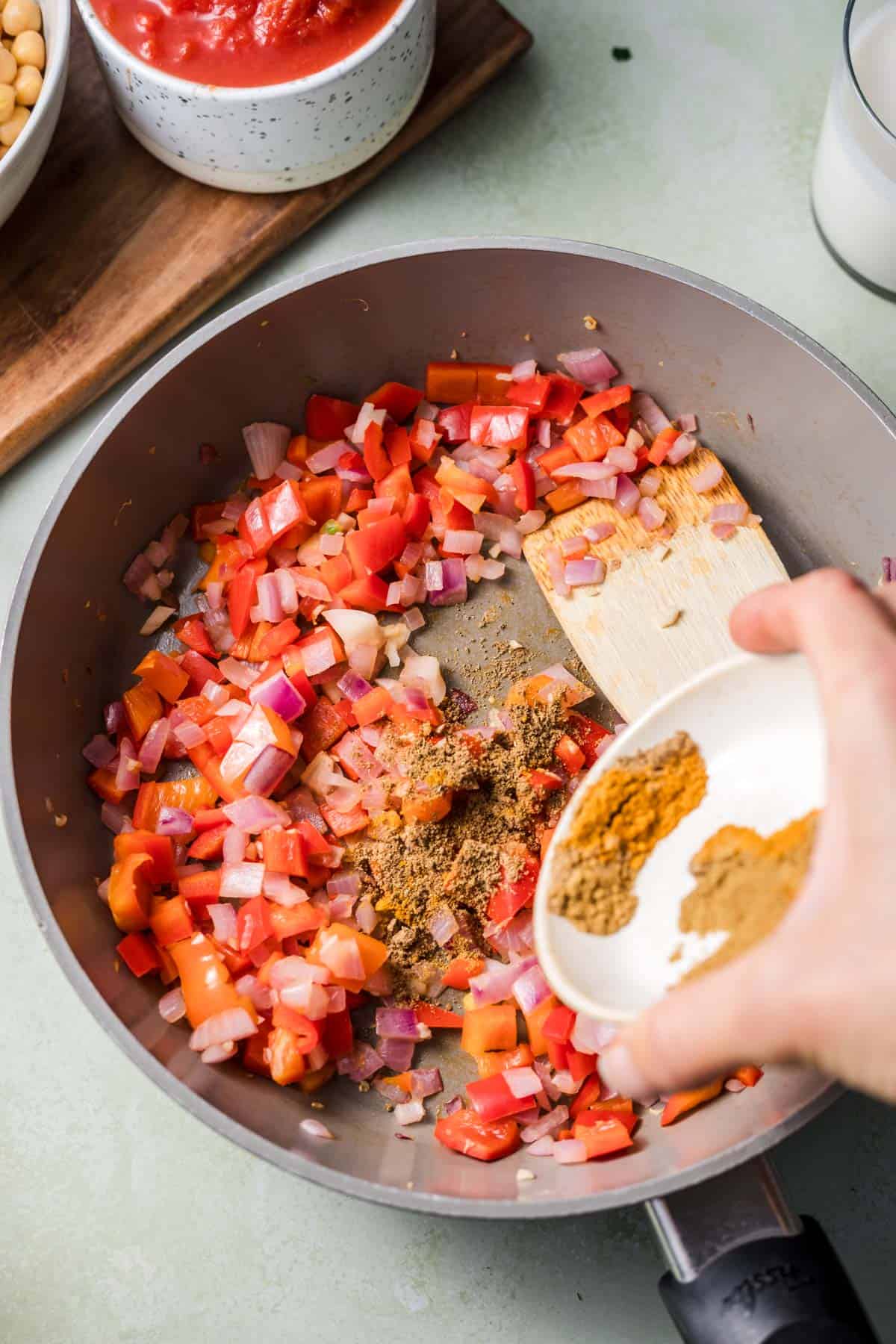 Adding spices to sautéed onion, garlic and red bell pepper in a pan