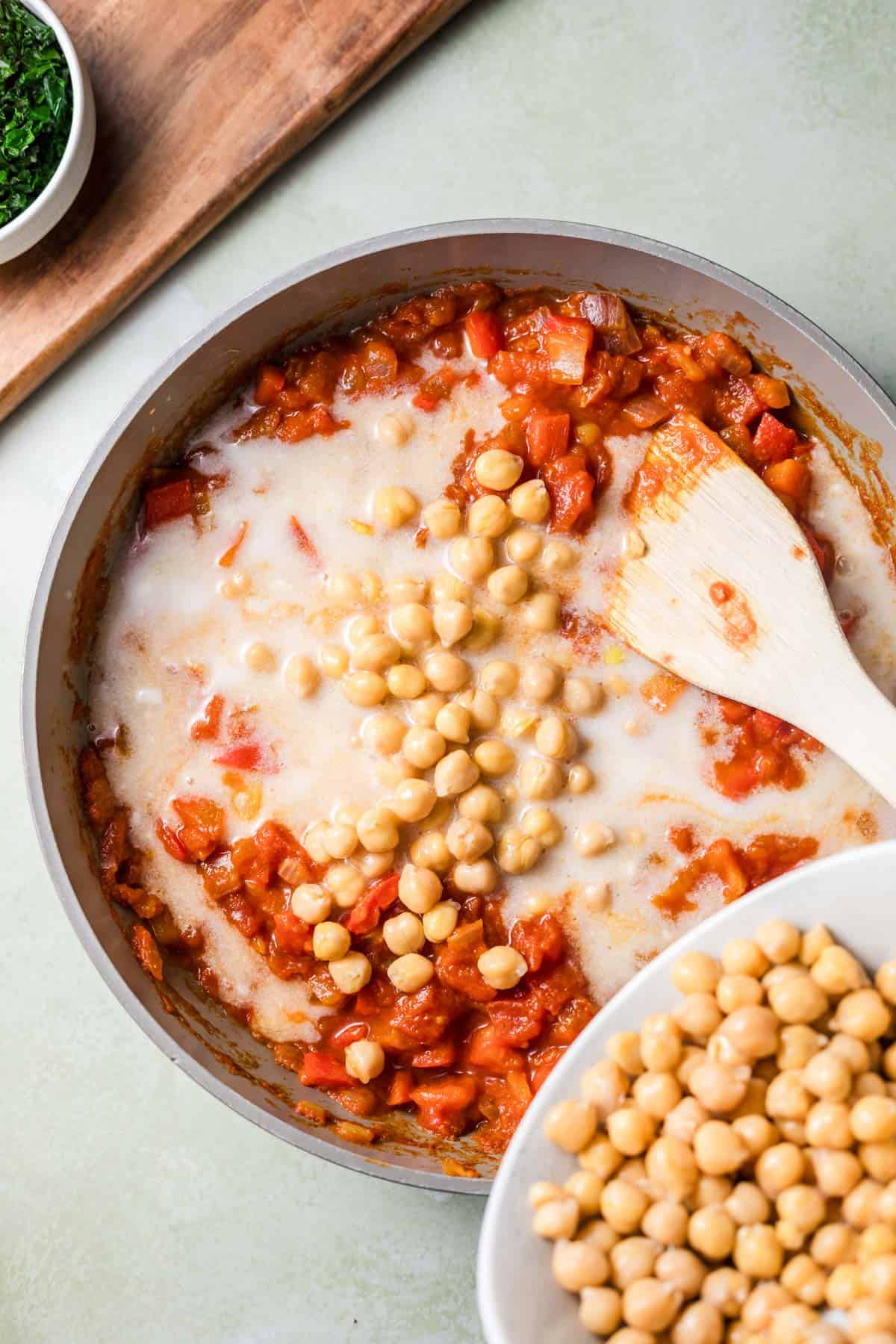 Stirring chickpeas into the tomato coconut curry sauce