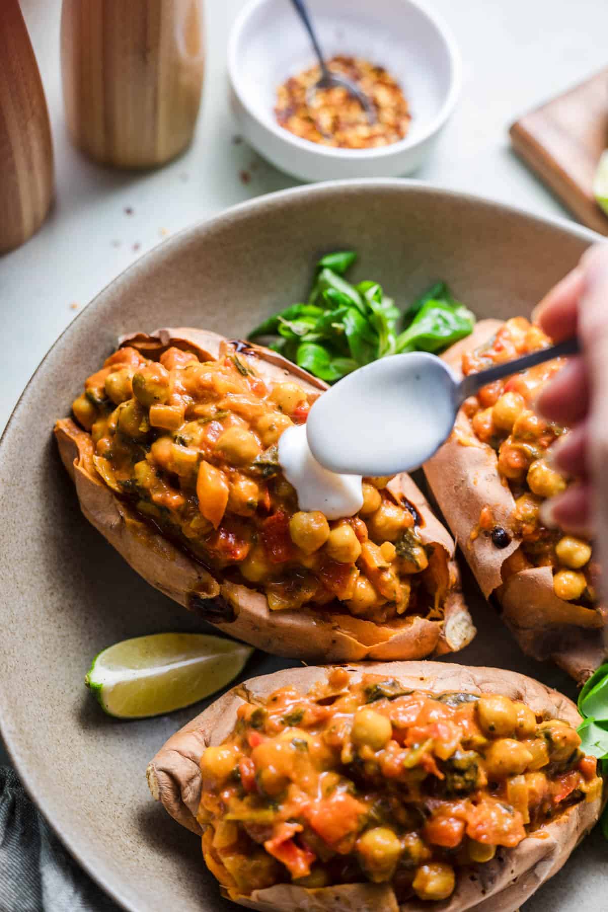 Stuffed sweet potatoes with chickpea curry and vegan yogurt sauce
