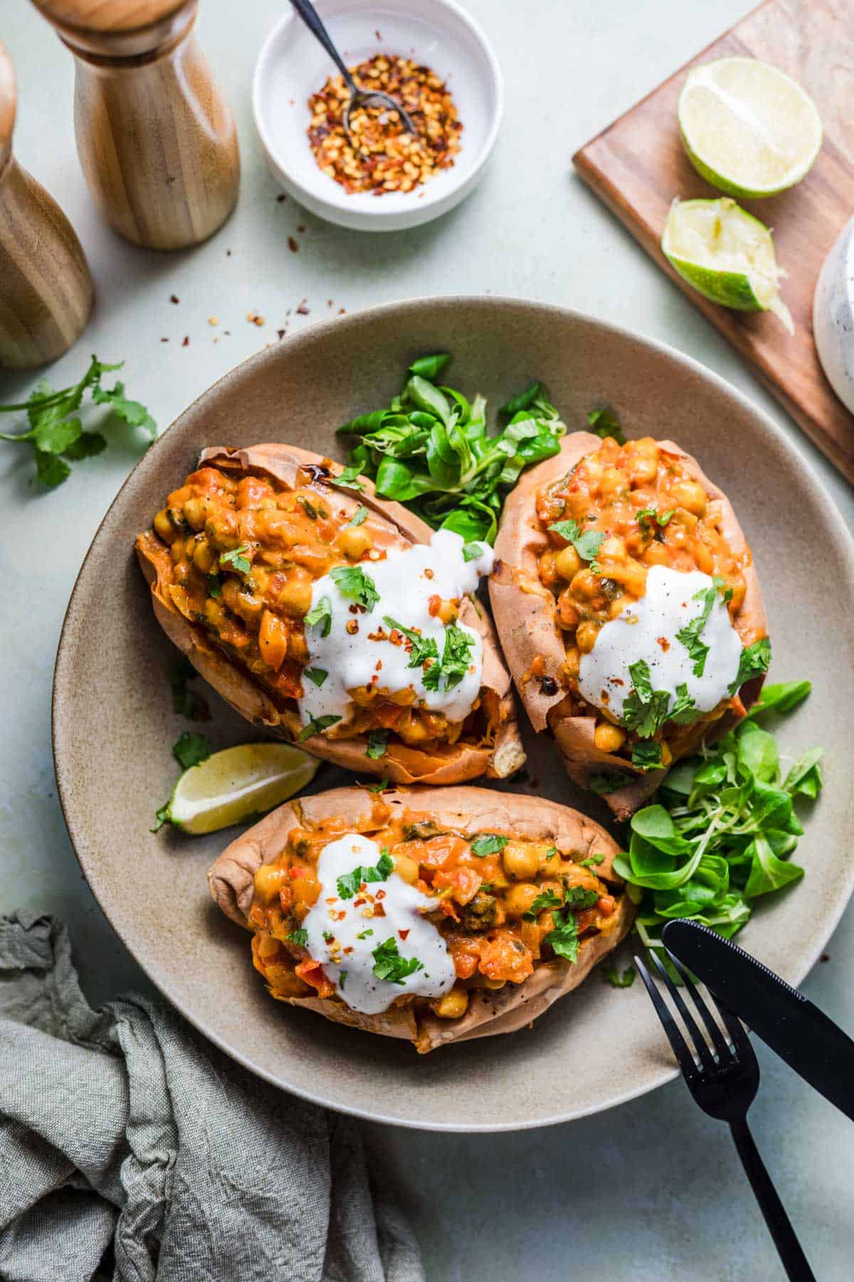Vegan baked sweet potatoes with chickpea curry filling, garnished with cilantro and sprouts