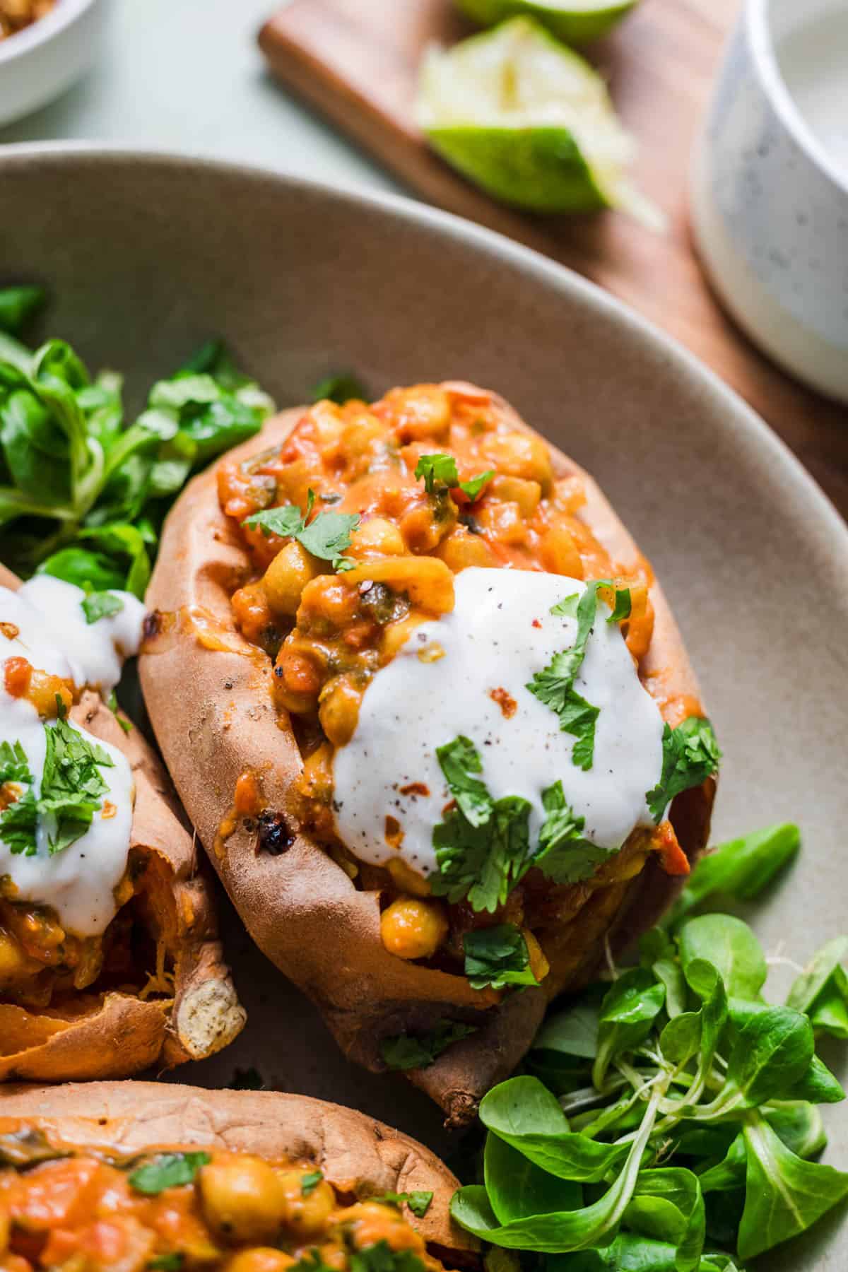 Oven-baked sweet potato stuffed with chickpea curry, topped with vegan yogurt sauce and fresh cilantro