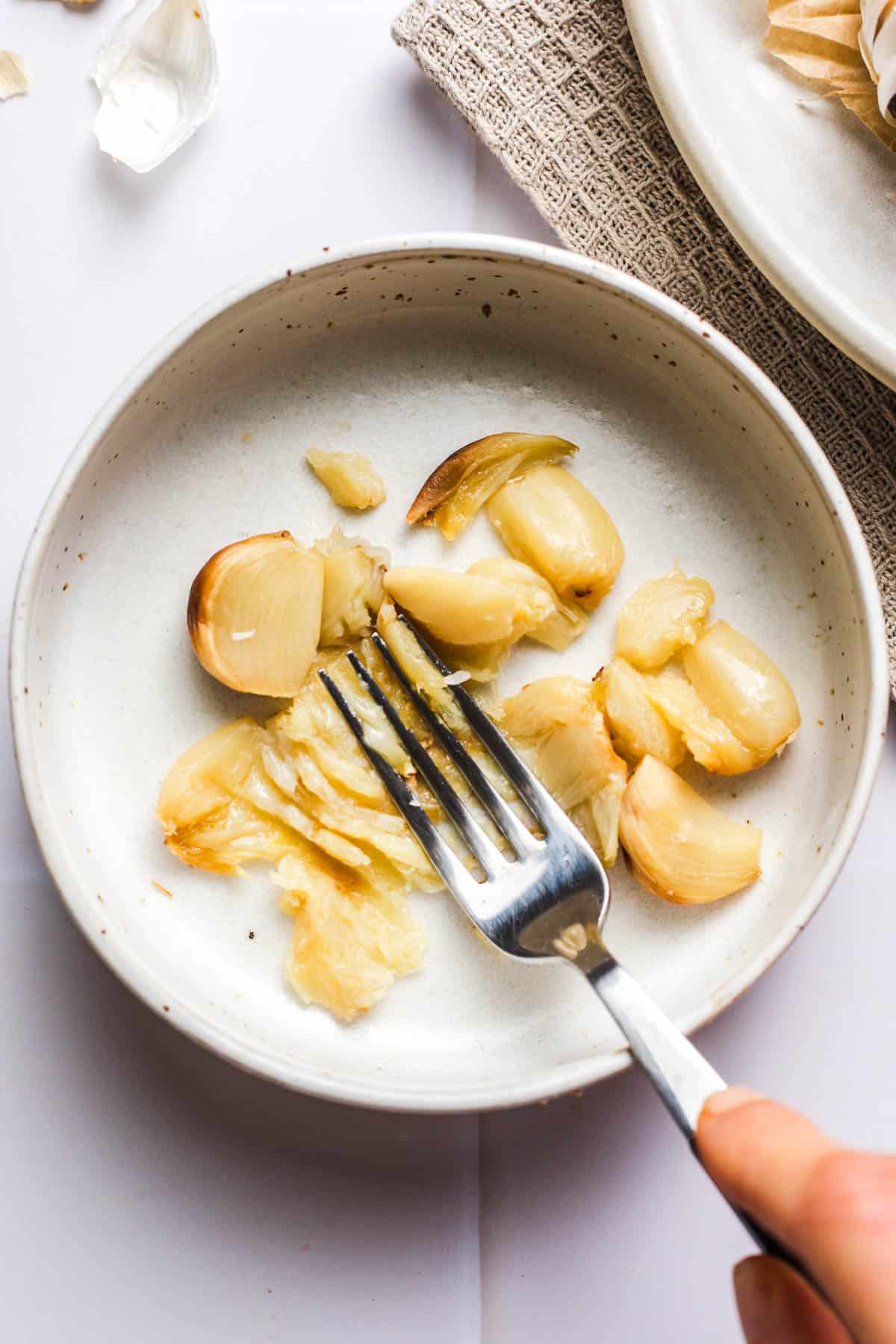geröstete knoblauchzehen mit gabel zerdrücken