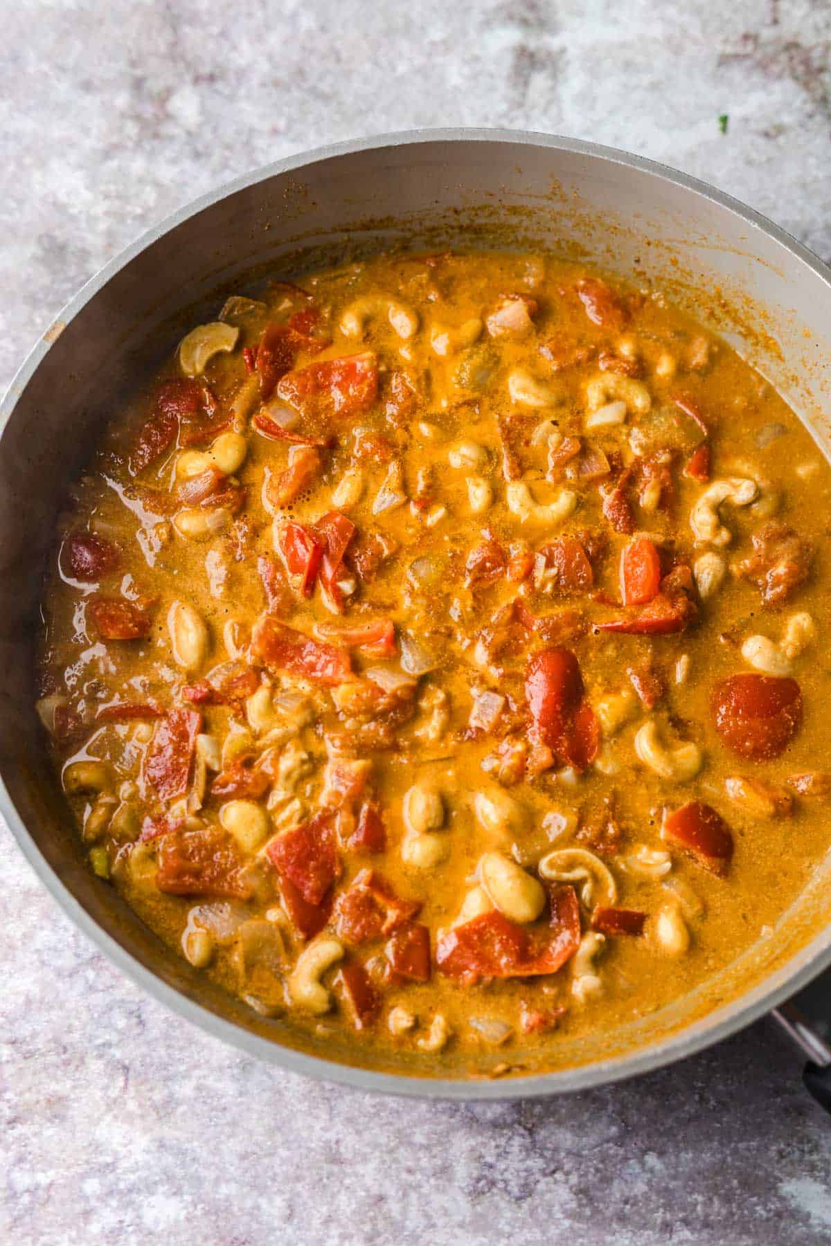 curry basis mit tomaten und cashews in pfanne